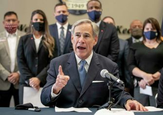 Texas Governor Greg Abbott speaking at a press conference about the law banning vaccine passports, with other officials in the background.