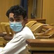 A man in a courtroom wearing a face mask, facing the camera. A man in a courtroom wearing a face mask, facing the camera.
