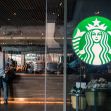 A Starbucks store with customers at the counter and the company logo prominently displayed. A Starbucks store with customers at the counter and the company logo prominently displayed.