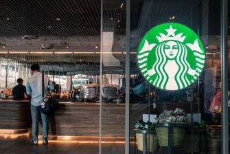 A Starbucks store with customers at the counter and the company logo prominently displayed.