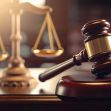 A gavel and scales of justice on a wooden legal desk, symbolizing a courtroom setting. A gavel and scales of justice on a wooden legal desk, symbolizing a courtroom setting.