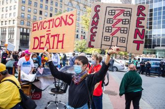 Protestors hold signs advocating against evictions and calling for rent cancellation during a demonstration.
