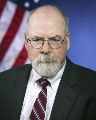 Portrait of John Durham, the special counsel appointed to investigate the origins of the Trump-Russia probe, with an American flag in the background.