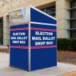 A blue mail ballot drop box with the text "ELECTION MAIL BALLOT DROP BOX" displayed prominently. A blue mail ballot drop box with the text "ELECTION MAIL BALLOT DROP BOX" displayed prominently.