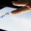 A close-up of a finger poised over the Google search page on a tablet, highlighting Google's search interface. A close-up of a finger poised over the Google search page on a tablet, highlighting Google's search interface.