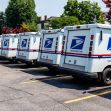 Row of U.S. Postal Service delivery trucks parked in a lot. Row of U.S. Postal Service delivery trucks parked in a lot.