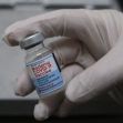A gloved hand holding a vial of the Moderna COVID-19 vaccine. A gloved hand holding a vial of the Moderna COVID-19 vaccine.