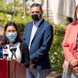 A press conference setting with three individuals discussing California's guaranteed income program, with microphones and a podium in view. A press conference setting with three individuals discussing California's guaranteed income program, with microphones and a podium in view.