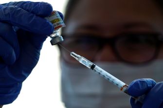 A healthcare professional prepares a vaccine syringe from a vial.