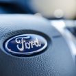 Close-up of a Ford logo on the steering wheel of a vehicle. Close-up of a Ford logo on the steering wheel of a vehicle.