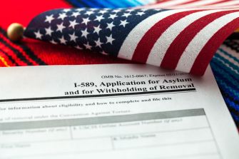 I-589 application form for asylum with American flag and traditional woven textile background.