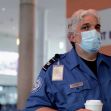 TSA employee wearing a mask while holding a coffee cup at an airport information desk. TSA employee wearing a mask while holding a coffee cup at an airport information desk.