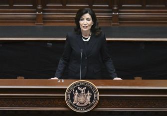 Governor Kathy Hochul speaking at a podium in a legislative setting.