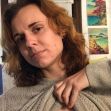 A woman in a gray sweater lifting her shirt to show scarring, expressing her experience with a double mastectomy. A woman in a gray sweater lifting her shirt to show scarring, expressing her experience with a double mastectomy.