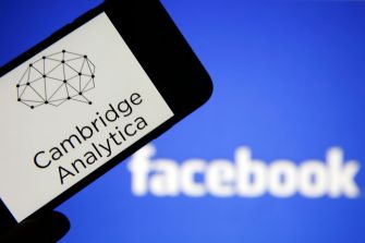 A smartphone displaying the Cambridge Analytica logo in front of the Facebook logo.