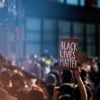 A protestor holds a sign that reads "BLACK LIVES MATTER" in a large crowd at a demonstration. A protestor holds a sign that reads "BLACK LIVES MATTER" in a large crowd at a demonstration.