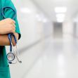A nurse in scrubs holding a stethoscope, standing in a hospital corridor. A nurse in scrubs holding a stethoscope, standing in a hospital corridor.