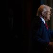 Donald Trump speaking at a podium, partially illuminated against a dark background. Donald Trump speaking at a podium, partially illuminated against a dark background.