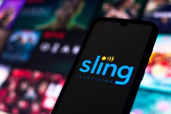 A smartphone displaying the Sling Television logo, with a blurred background of various streaming content.