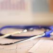 Stethoscope resting on medical charts with graphs in the background. Stethoscope resting on medical charts with graphs in the background.