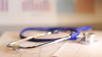 Stethoscope resting on medical charts with graphs in the background.