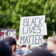 A crowd holding signs at a protest, with one prominent sign reading "BLACK LIVES MATTER." A crowd holding signs at a protest, with one prominent sign reading "BLACK LIVES MATTER."