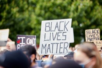 A crowd holding signs at a protest, with one prominent sign reading "BLACK LIVES MATTER."