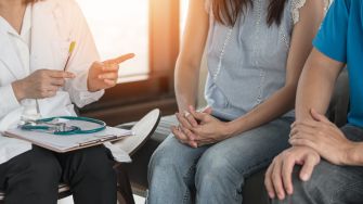 A doctor consulting with a couple in a medical setting.
