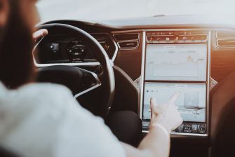 A person interacting with the touchscreen interface of a Tesla vehicle, showcasing autonomous driving features.