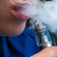 Close-up of a person exhaling vapor from an e-cigarette or vaping device. Close-up of a person exhaling vapor from an e-cigarette or vaping device.