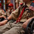 A group of Boy Scouts sitting together, wearing uniforms and hats, during a meeting or event. A group of Boy Scouts sitting together, wearing uniforms and hats, during a meeting or event.