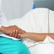 A medical professional holds the hand of a patient in a hospital setting, emphasizing the compassionate care provided in emergency situations. A medical professional holds the hand of a patient in a hospital setting, emphasizing the compassionate care provided in emergency situations.