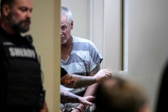 Colin Gray, the father of a Georgia high school shooter, appears in court wearing a striped jail uniform, surrounded by law enforcement officers.
