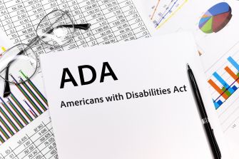 Document titled "ADA: Americans with Disabilities Act" with glasses and charts in the background.