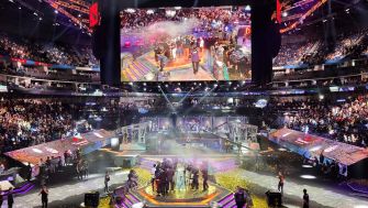 A large esports event with spectators, a stage featuring gaming setups, and a celebratory atmosphere.