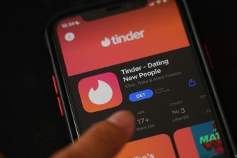 A person interacting with the Tinder dating app on a mobile phone.