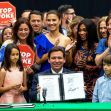 Governor Ron DeSantis holding a signed document promoting the "Stop WOKE Act" surrounded by supporters, including children and individuals holding "Stop WOKE" signs. Governor Ron DeSantis holding a signed document promoting the "Stop WOKE Act" surrounded by supporters, including children and individuals holding "Stop WOKE" signs.