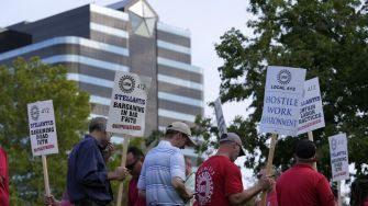 Workers participating in a UAW strike, holding signs calling for better labor practices and working conditions.