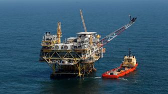 Oil drilling platform in the ocean with a supply boat alongside.