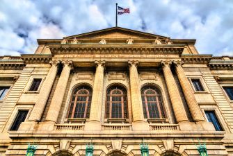 Facade of a historic courthouse with columns and an American flag flying above against a cloudy sky.
