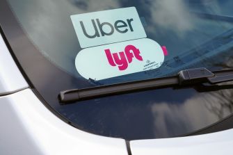 Uber and Lyft decals displayed on a car's windshield.