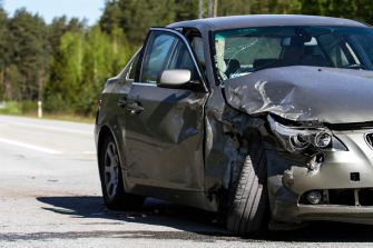 A damaged car on the side of the road after a collision.