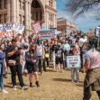 Demonstrators gather outside a building holding signs in support of transgender rights and against Texas Governor Abbott's order regarding gender-affirming care for minors. Demonstrators gather outside a building holding signs in support of transgender rights and against Texas Governor Abbott's order regarding gender-affirming care for minors.