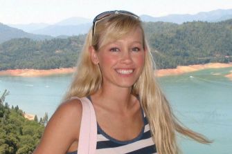 Sherri Papini smiling near a scenic lake with mountains in the background.