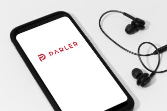 Image of a smartphone displaying the Parler logo alongside earphones.