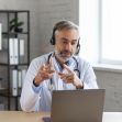 A physician wearing a headset, engaged in a telemedicine consultation via laptop. A physician wearing a headset, engaged in a telemedicine consultation via laptop.