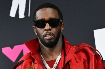 Sean “Diddy” Combs at an event, wearing sunglasses and a red jacket.