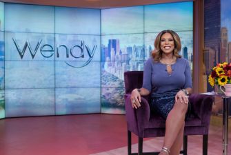 Wendy Williams seated on set with a vibrant backdrop during her television show.