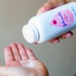 A person pouring Johnson & Johnson baby powder into their hand. A person pouring Johnson & Johnson baby powder into their hand.