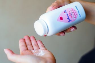 A person pouring Johnson & Johnson baby powder into their hand.